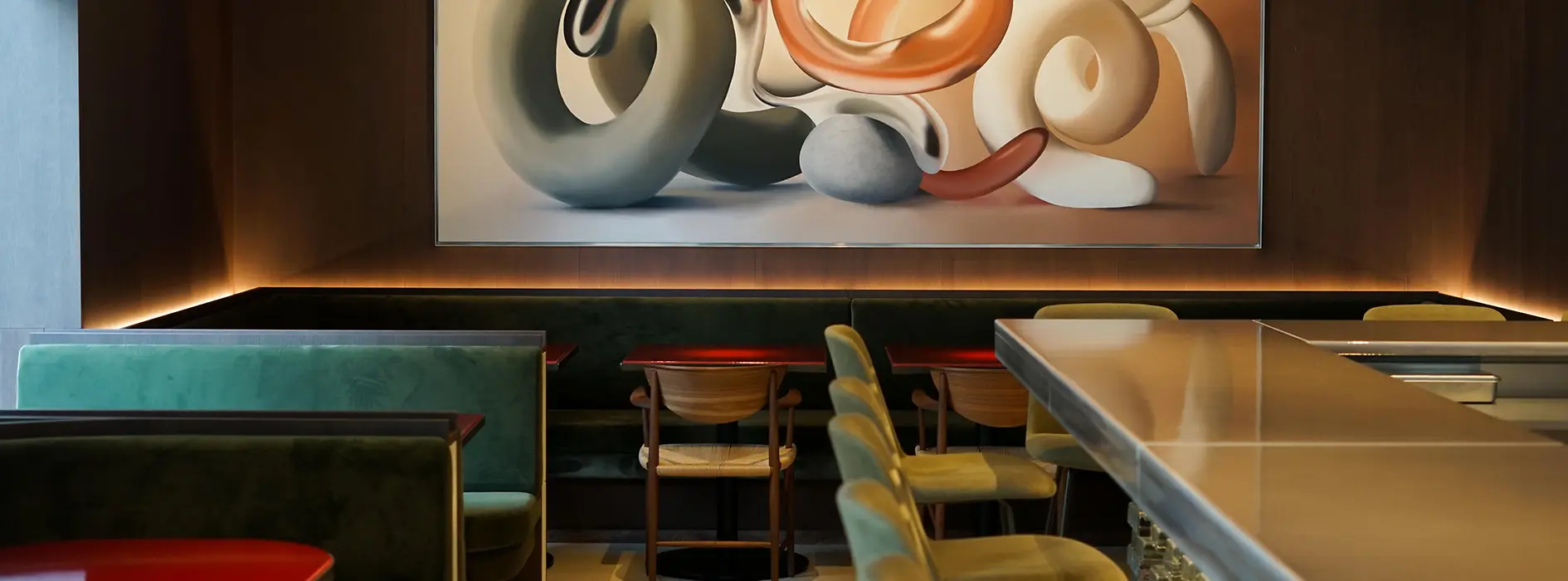 A stylish restaurant interior with green upholstered seating, a long counter, and a large abstract artwork featuring intertwined sculptural forms.