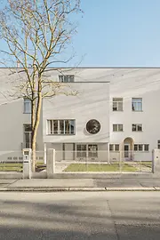Street view of the modernist villa with circular window and recessed entrance.
