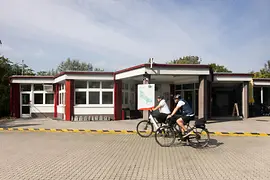 Two cyclists in front of the entrance to the MICAMPA Wien Donau campground