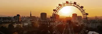 Ferris wheel in the Vienna Prater, Vienna skyline at sunset in the background