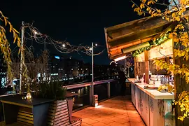 Persone che bevono punch su una terrazza con vista sul canale del Danubio