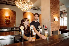 Two people with beer behind the bar