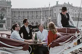 People dining in a horse-drawn carriage in front of Imperial Palace