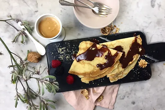 Zwei Schoko-Nuss-Palatschinken mit Kaffee und Besteck serviert