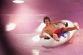 Kind rutscht mit Reifen über die Wasserrutsche in der Therme Wien