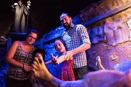 Una familia con un niño y la figura de un muerto en la fosa