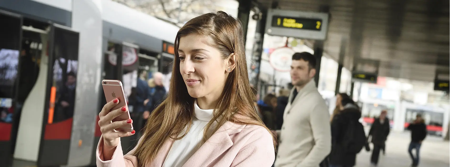 Students in a subway station looking at a mobile phone