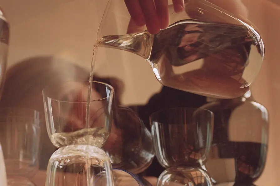 Woman pouring water from a carafe into water glasses