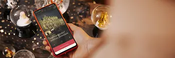 Smartphone con una schermata di ivie, incorniciato da palle di neve