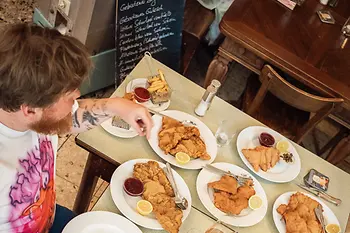 Two people at a table with numerous Wiener schnitzels