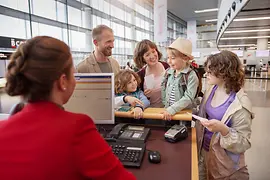 A young family with three children at the Austrian Airlines check-in counter at Vienna Airport