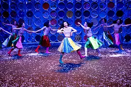 Korean dancers twirl around the stage in colorful skirts and boots.