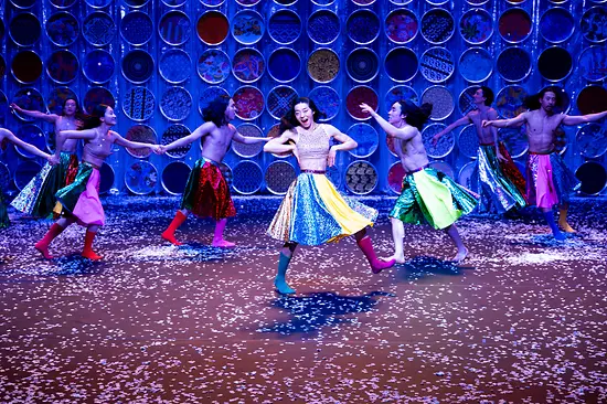 Korean dancers twirl around the stage in colorful skirts and boots.