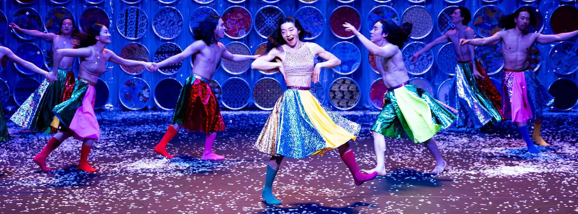 Korean dancers twirl around the stage in colorful skirts and boots.