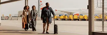 ウィーン空港の屋外エリアで手荷物を持ち、ターミナルへ向かう人々