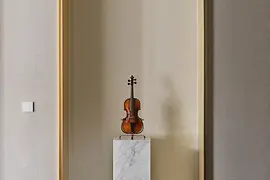 Violin on a marble pedestal in a tall, rounded wall niche. 