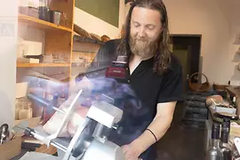 Homme tranchant du jambon à l’épicerie fine Babo & Lenz à Vienne